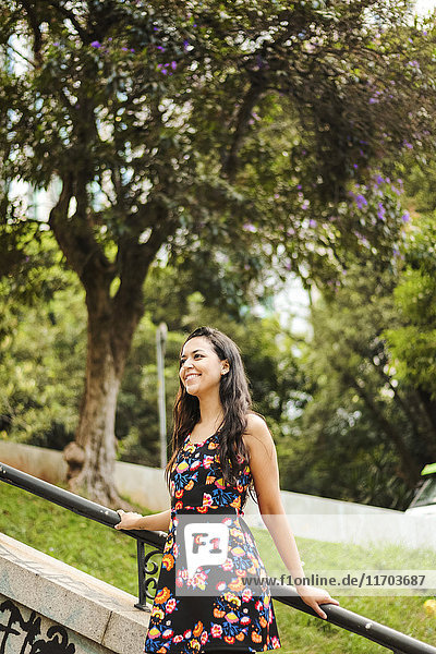 Lächelnde junge Frau im Sommerkleid mit Blumenmuster