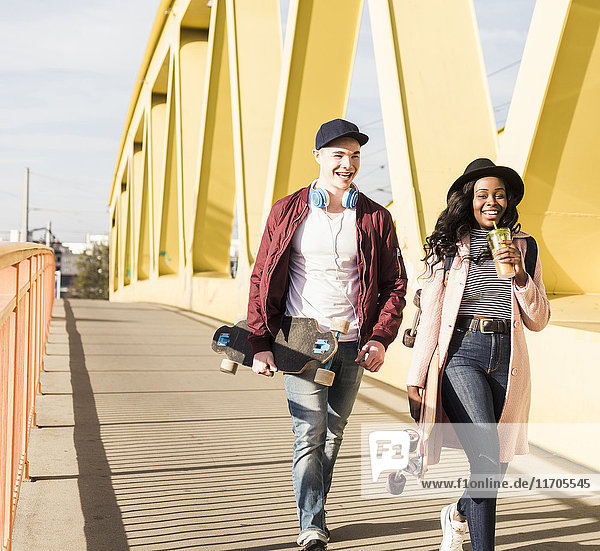 Junges Paar mit Skateboard auf der Brücke