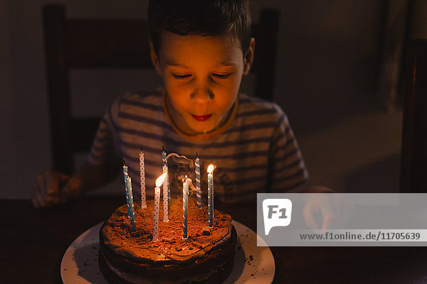 Boy blowing out burning candles on his birthday cake