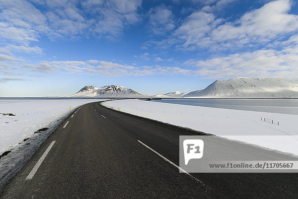 Leere Straße durch Island mit Bergen im Hintergrund