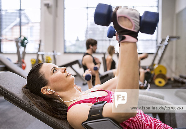 Young woman exercising with dumbbells in gym