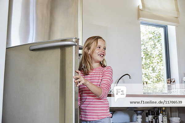 Smiling little girl opening fridge