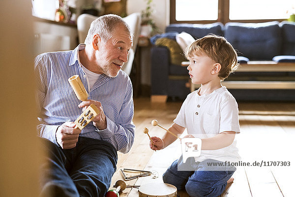 Großvater und Enkel spielen zu Hause Musik.