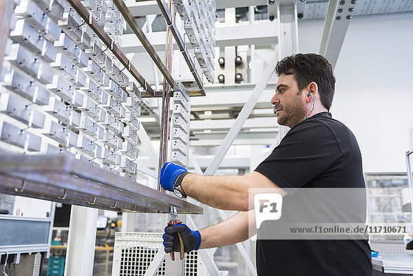 Man working in factory shop floor hanging products on rack