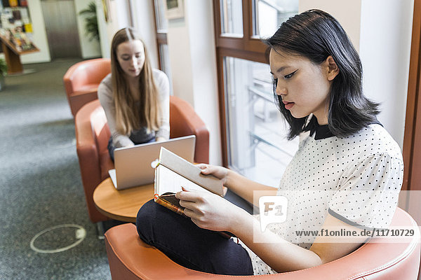 Teenagermädchen beim Lesen eines Buches in einer öffentlichen Bibliothek