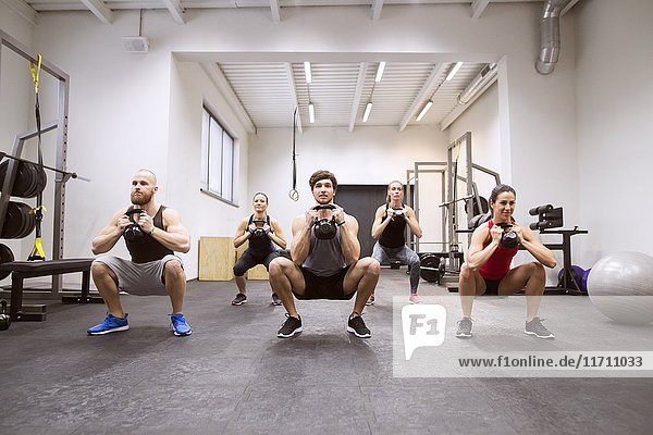 Group of athletes exercising with kettlebells in gym