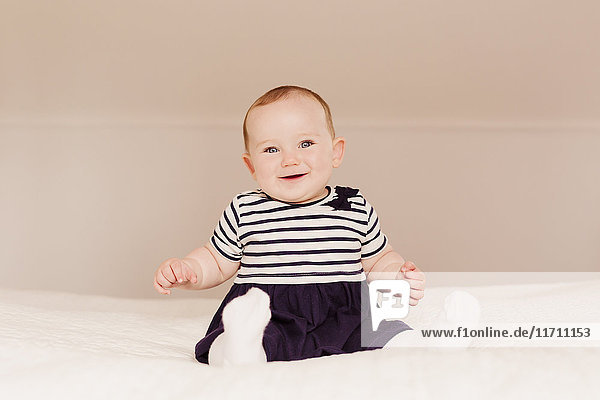 Portrait of smiling baby girl sitting on bed