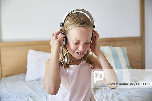 Porträt eines lächelnden kleinen Mädchens  das zu Hause Musik mit Kopfhörern hört.