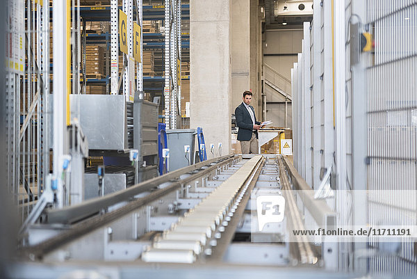 Businessman at conveyor belt in factory