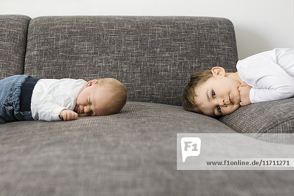 Sleeping newborn baby boy and his brother on couch