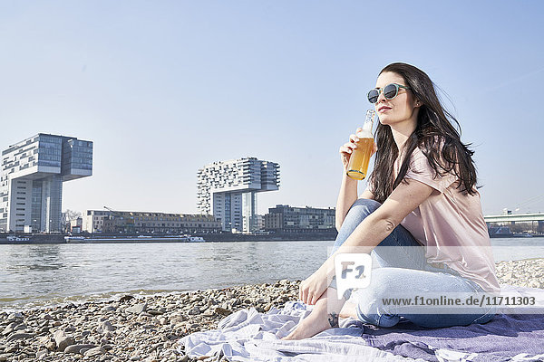 Deutschland  Köln  junge Frau entspannt und bei einem Bier am Rhein