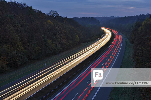 Deutschland Bayern Ampelpfade auf der Autobahn bei Dämmerung