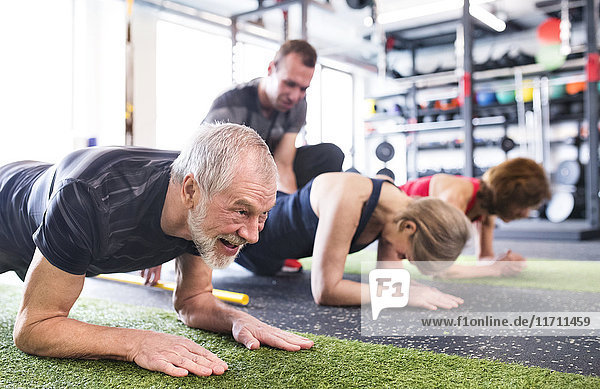 Gruppe von fitten Senioren mit Personal Trainer im Fitnessstudio