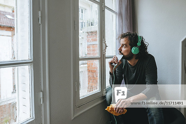 Mann hört Musik mit Kopfhörer und Smartphone zu Hause