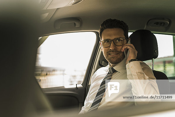 Erfolgreicher Geschäftsmann am Telefon im Auto sitzend