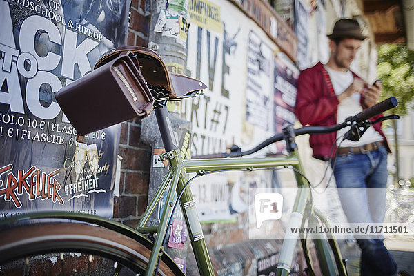 Deutschland  Hamburg  St. Pauli  Mann mit Smartphone und Fahrrad im Vordergrund