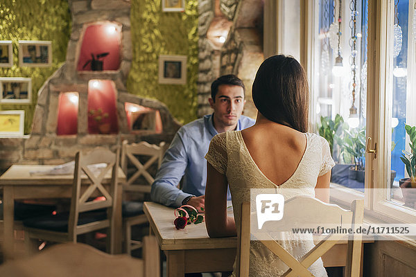 Rückansicht einer jungen Frau  die von Angesicht zu Angesicht mit ihrem Freund am Tisch in einem Restaurant sitzt.
