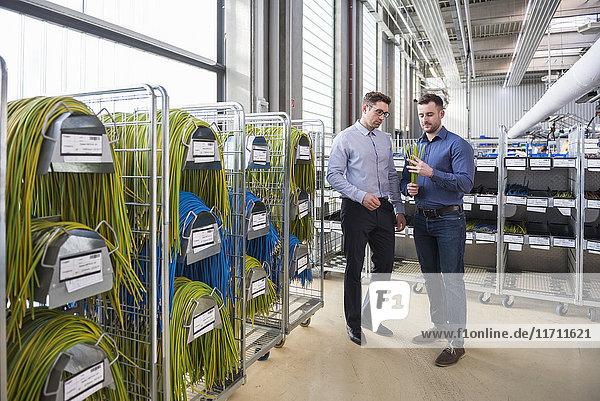 Two men in factory shop floor examining product