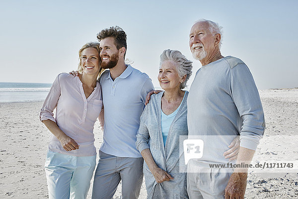 Smiling senior couple with adult children on the beach