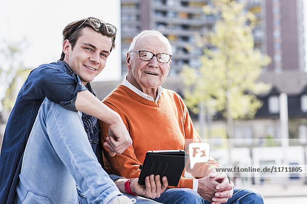 Porträt eines lächelnden älteren Mannes und erwachsenen Enkels mit Tablette