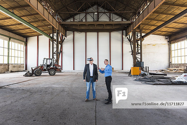 Two businessmen with VR glasses talking in old industrial hall