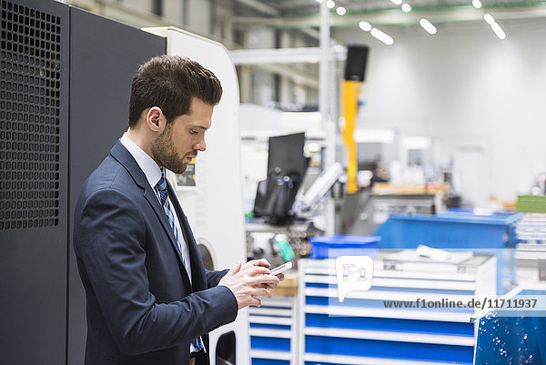 Businessman in factory shop floor using cell phone