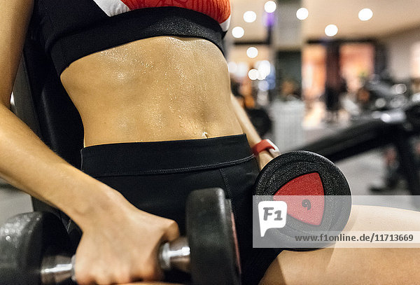Close-up of woman lifting dumbbells in gym