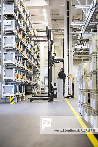 Worker operating forklift in factory warehouse