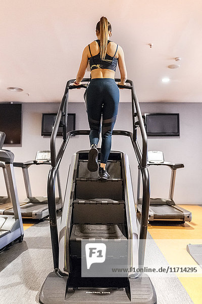 Junge Frau beim Training im Fitnessstudio mit einer Treppenmaschine