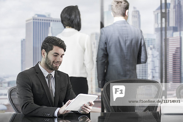 Smiling businessman using tablet in boardroom