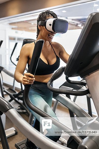 Woman wearing VR glasses on an elliptical traine in the gym