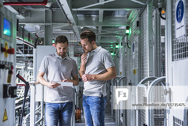 Two men in automatized high rack warehouse looking at tablet