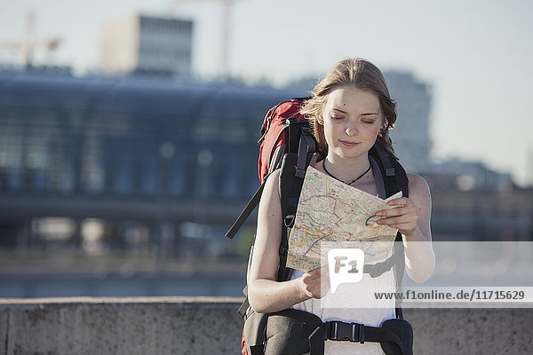 Deutschland  Berlin  Junge Frau mit Rucksack auf der Landkarte