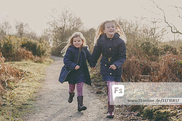 Two sisters running on a rural path together