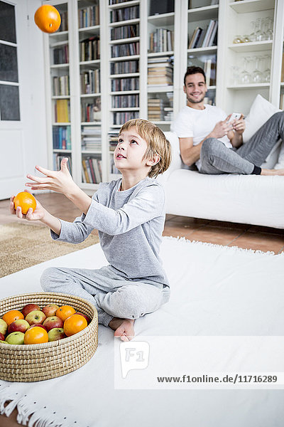 Junge jongliert mit Orangen zu Hause