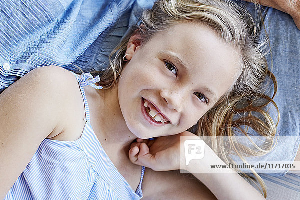 Porträt eines lächelnden kleinen Mädchens mit Zahnlücke auf dem Schoß der Mutter.
