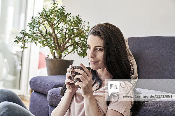 Junge Frau mit Kaffeetasse zu Hause