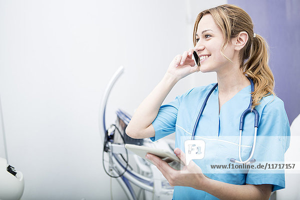 Smiling doctor on the phone holding tablet