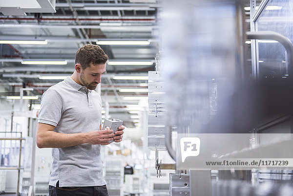 Man with tablet in factory shop floor examining products