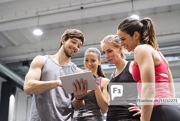 Gruppe von glücklichen Athleten mit Tablette nach dem Training im Fitnessstudio