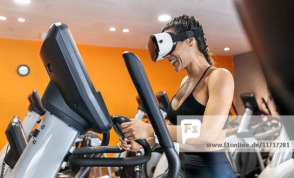Frau mit VR-Brille auf einem Ellipsentrainer in der Turnhalle