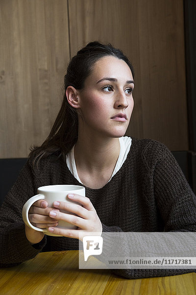 Porträt einer ernsten Frau mit einer Tasse Kaffee im Coffee Shop