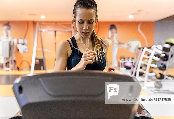 Junge Frau trainiert im Fitnessstudio auf einem Treadmil