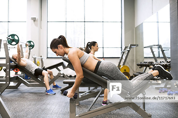 Young woman exercising with dumbbells in gym