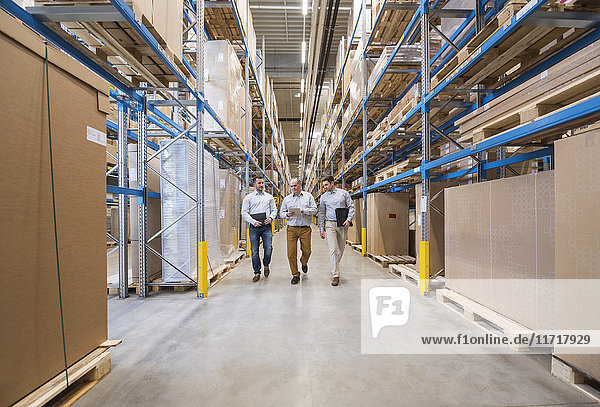 Three men walking in factory warehouse
