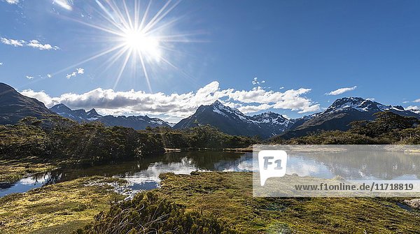 Sonne auf kleinem Bergsee mit Spiegelung einer Bergkette  Key Summit Track  Fiordland National Park  Southland Region  Neuseeland  Ozeanien