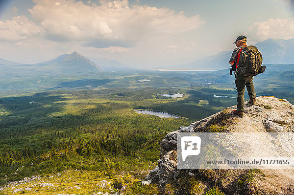Backpacker overlooks scenic view from a bluff high above  Wrangell-St. Elias National Park  Southcentral Alaska  USA