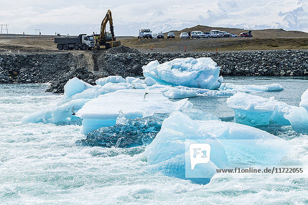 Ein Bagger sitzt am Ufer der Gletscherlagune Jokulsarlon in Island und ist bereit  Eisstaus zu beseitigen  wenn sie den See in Richtung Atlantik verlassen; Jokulsarlon  Island'.
