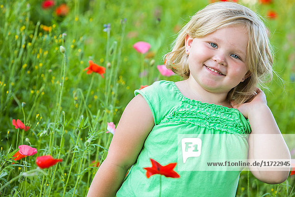 Ein junges Mädchen mit blondem Haar steht in einem Feld mit bunten Mohnblumen; Oregon  Vereinigte Staaten von Amerika'.