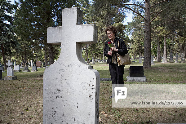 Eine Frau besucht ein Grab auf einem Friedhof; Edmonton  Alberta  Kanada .